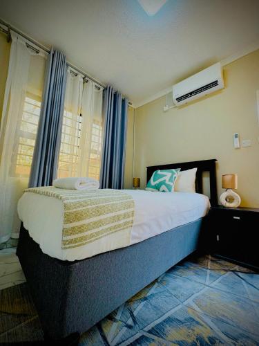 a bedroom with a large bed with blue curtains at Nouvelle BNB in Gaborone
