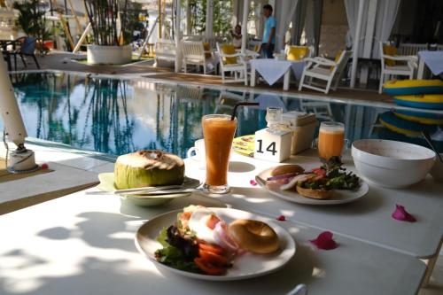a table with plates of food and drinks next to a pool at To The Moon Guesthouse in Chiang Mai