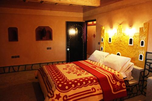 Schlafzimmer mit einem Bett mit einer roten und weißen Decke in der Unterkunft La Kasbah De Dades in Boumalne