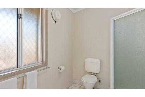 a white bathroom with a toilet and a window at Discovery Parks - Port Hedland in Port Hedland