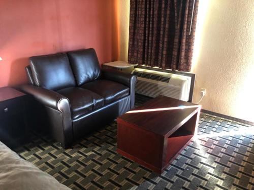 a living room with a leather couch and a table at Executive inn motel & RV Park in Woodward