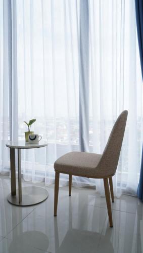 a chair and a table in front of a window at Blue Belle Staycation Pollux Habibie in Batam Center