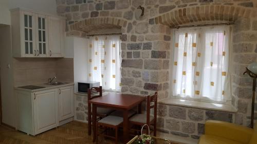 a kitchen with a table and a stone wall at Apartments Popovic in Kotor