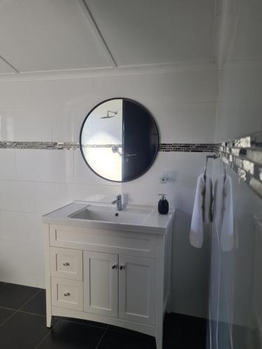 a white bathroom with a sink and a mirror at Palm Bliss Self Catering Accommodation in Durban
