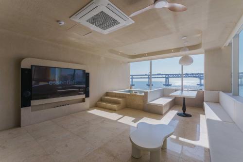 a living room with a television and a couch and a table at Meomulda Gwangalli Gamsung in Busan