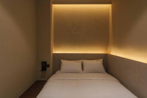 a bed with two pillows in a small room at Meomulda Gwangalli Gamsung in Busan