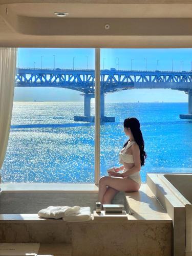 a woman sitting on a bench in front of a bridge at Meomulda Gwangalli Gamsung in Busan
