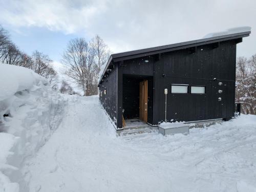 a black building with a door in the snow at Taki - Annupuri Riverside Chalet in Niseko