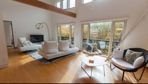 a large living room with white furniture and windows at Taki - Annupuri Riverside Chalet in Niseko