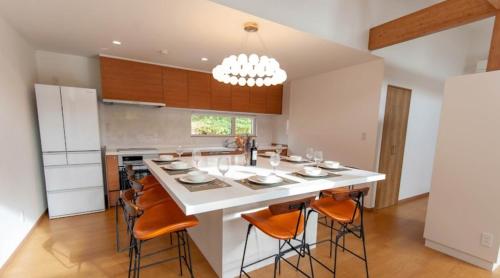 a kitchen with a large white island with orange chairs at Taki - Annupuri Riverside Chalet in Niseko