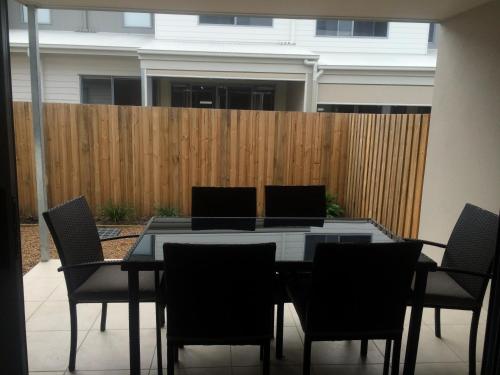 a dining room table with chairs and a fence at Direct Collective - Breeze on Brightwater in Mooloolaba