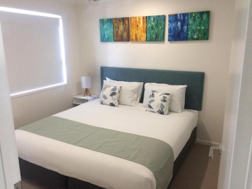 a bedroom with a bed with two paintings on the wall at Direct Collective - Breeze on Brightwater in Mooloolaba