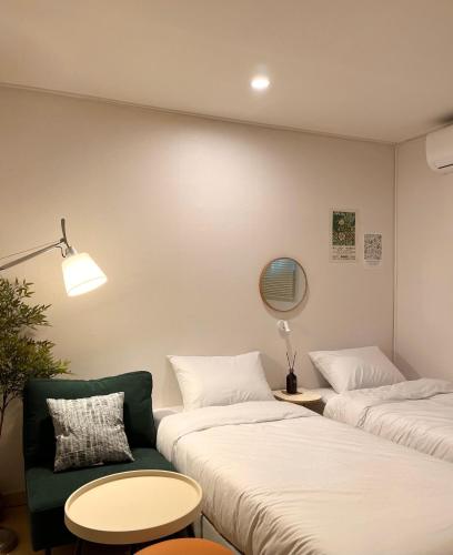 Habitación con 2 camas, silla y mesa. en Yellow stay, en Bucheon