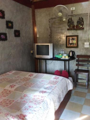 a bedroom with a bed and a tv on the wall at Baankanoonpai(บ้านขนุนปาย)​ in Pai