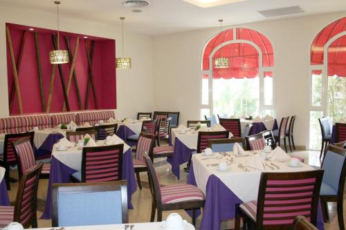 a dining room with tables and chairs and red curtains at Ramada Plaza by Wyndham Veracruz Boca del Rio in Veracruz