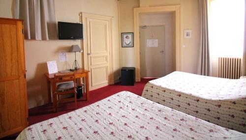 a hotel room with two beds and a desk at Hôtel Adour in Pau
