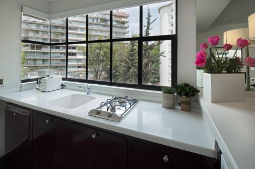 a kitchen with a sink and a large window at FlowSuites Polanco in Mexico City