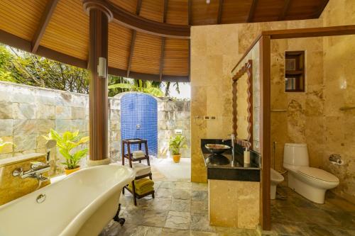 a bathroom with a tub and a toilet and a sink at Sun Siyam Olhuveli in South Male Atoll