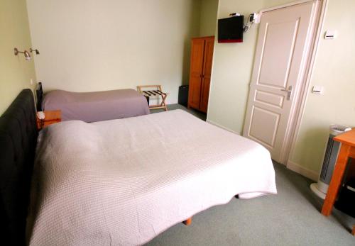 a bedroom with a white bed and a door at Hôtel Adour in Pau