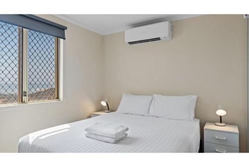 a bedroom with a white bed with two towels on it at Discovery Parks - Port Hedland in Port Hedland