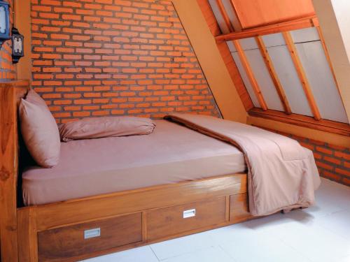 a bed in a room with a brick wall at Villa Andhita Pantai Garut in Mancagahar
