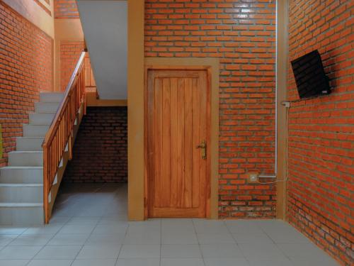 a brick hallway with a wooden door and stairs at Villa Andhita Pantai Garut in Mancagahar