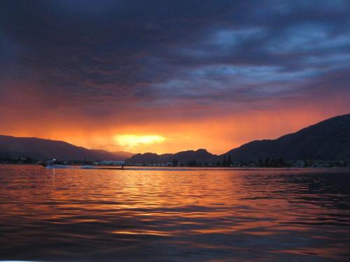 a sunset over a body of water with mountains at Casa Del Mila Oro Condo in Osoyoos