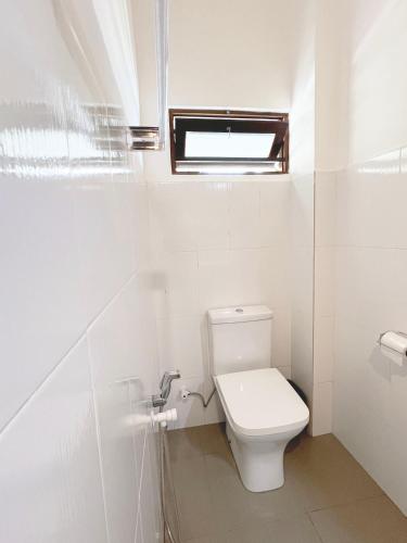 a white bathroom with a toilet and a window at Sailors' Bay in Hikkaduwa