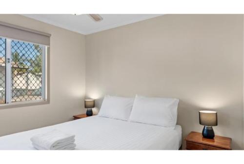 a bedroom with a white bed with two lamps at Discovery Parks - Port Hedland in Port Hedland