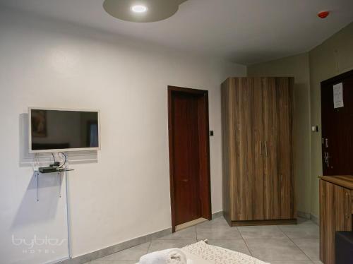 a room with a tv on the wall and a door at Byblos Hotel-Sky Osu in Accra