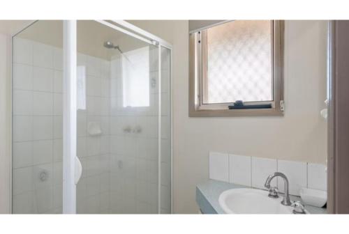 a white bathroom with a shower and a sink at Discovery Parks - Port Hedland in Port Hedland