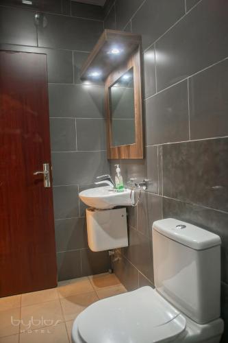 a bathroom with a toilet and a sink and a mirror at Byblos Hotel-Sky Osu in Accra