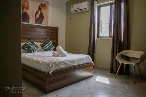 a bedroom with a bed and a chair and a window at Byblos Hotel-Sky Osu in Accra