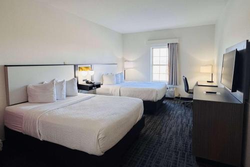 a hotel room with two beds and a flat screen tv at Ramada by Wyndham Sparta/At Speedway in Sparta