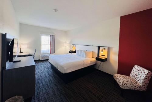 a hotel room with a bed and a chair at Ramada by Wyndham Sparta/At Speedway in Sparta
