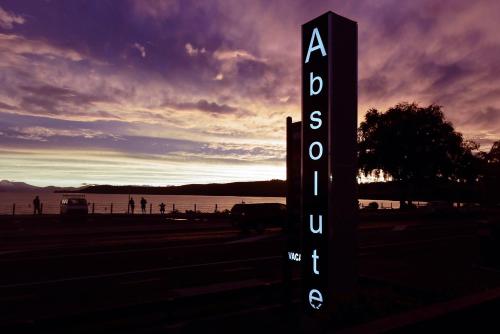 a sign in front of a body of water with a sunset at Absolute Lake View Motel in Taupo