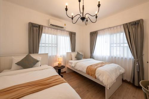 une chambre avec deux lits et un lustre dans l'établissement SpringDay House , Pool Villa Near Nimman, à Chiang Mai