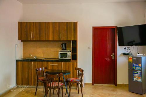 a kitchen with a table and chairs and a red door at Byblos Hotel-Sky Osu in Accra