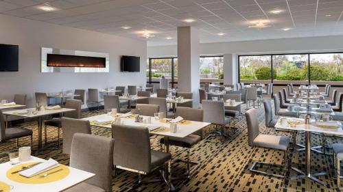 a dining room with tables and chairs and windows at Hilton San Francisco Airport Bayfront - No Resort Fee in Burlingame