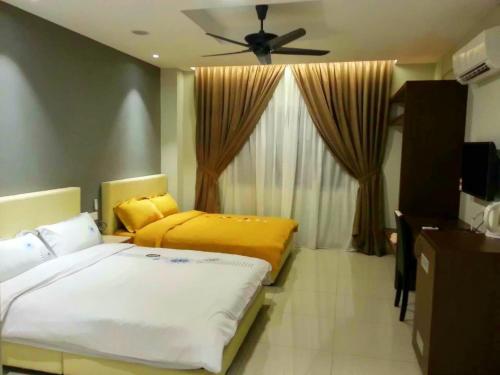 Un dormitorio con dos camas y un ventilador de techo. en Malacca Hotel Apartment, en Melaka