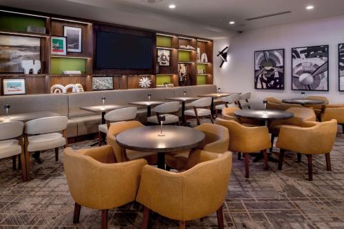 a restaurant with tables and chairs and a flat screen tv at Hilton St. Louis Airport in Woodson Terrace