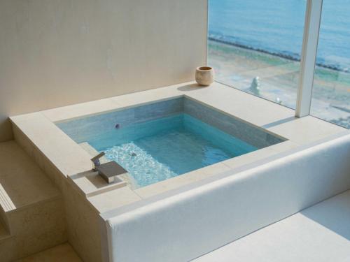 a tub in a bathroom with a view of the ocean at Meomulda Gwangalli Gamsung in Busan