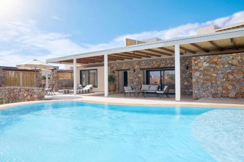 a swimming pool in front of a villa at Mirabello Bay Luxury Resort in Agios Nikolaos