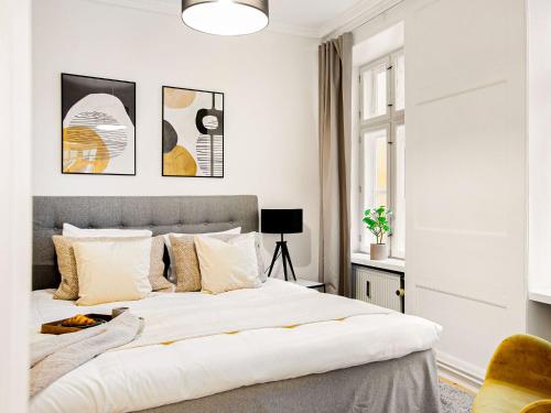 a white bedroom with a large bed and a window at Sanders Tivoli 1- Lovely 2-Bdr Apt near Tivoli in Copenhagen