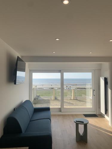 a living room with a blue couch and a view of the ocean at Hardelot Face Mer in Hardelot-Plage