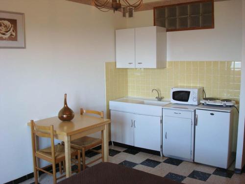 a kitchen with white cabinets and a table and a microwave at Hôtel Restaurant Sole e Monte in Cuttoli-Corticchiato