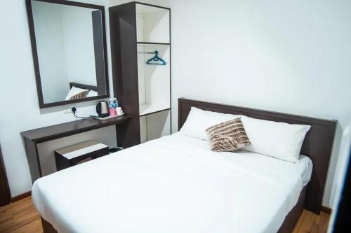 a bedroom with a white bed and a mirror at Shuang Ling Inn in Miri