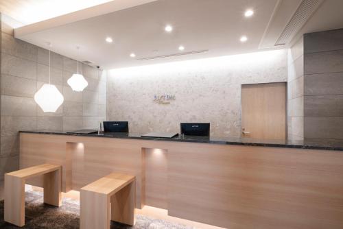 an office with a reception desk with two desks and benches at Just Inn Premium Toyohashi Station in Toyohashi