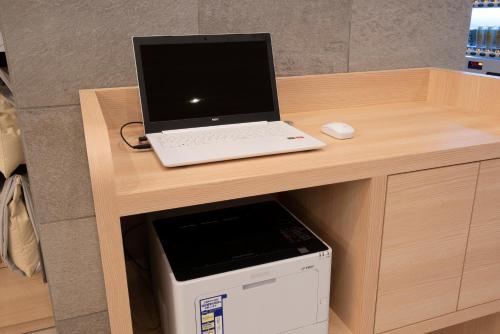 a laptop computer sitting on a desk next to a microwave at Just Inn Premium Toyohashi Station in Toyohashi