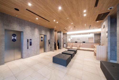 a lobby with a waiting room with couches and a table at Just Inn Premium Toyohashi Station in Toyohashi